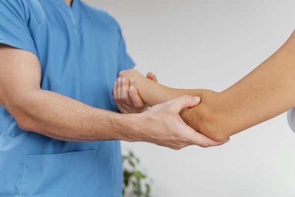 side-view-male-osteopathic-therapist-checking-female-patient-s-elbow-joint-movement